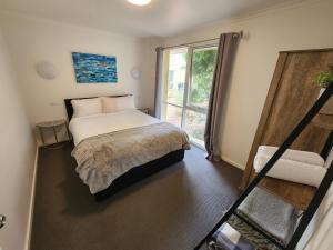 托基Bells Beach Cottages - Pet friendly cottage with wood heater的一间卧室设有一张床和一个大窗户