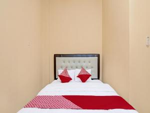 北干巴鲁OYO 91835 Djasur Kost的一间卧室配有红色和白色枕头的床