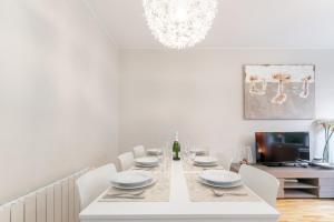 巴塞罗那Elegance Barcelona Rentals的餐桌、白色椅子和电视