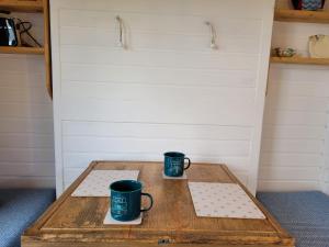 绿岛The Shepherds Hut at Forestview Farm的木桌旁的两杯咖啡