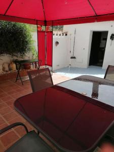 CútarCASA PACO - Maison Andalousie的露台的红色遮阳伞下的桌椅