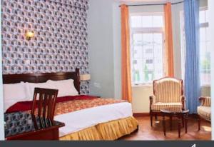 阿克拉国会酒店的一间卧室配有一张床、两把椅子和一个窗户