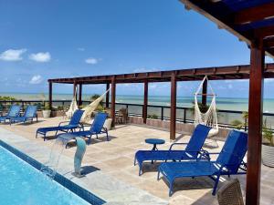 若昂佩索阿MARINAS PRAIA Flat - Cabo Branco by PenareiaTurBr的一个带蓝色椅子的游泳池,背景是大海