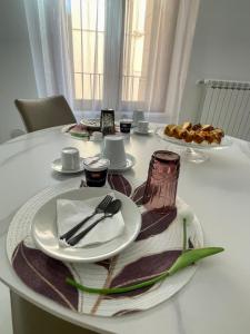 拉奎拉B & B Piazza Angioina的桌子上带盘子和餐具的桌子