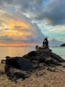 合艾Pani House Hatyai 1的坐在海滩上岩石上的一对夫妇