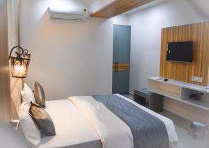 艾哈迈达巴德Hotel The Grand Crystal的卧室配有一张床,墙上配有电视。