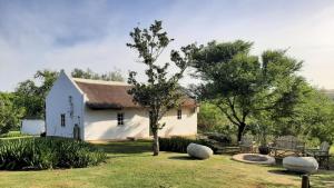 里弗斯代尔Zeekoegat Historical Homestead的院子中一棵树的小白色房子