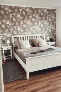 埃姆登Ferienwohnung Ostfriesenherz Emden的卧室配有白色的床和花卉壁纸