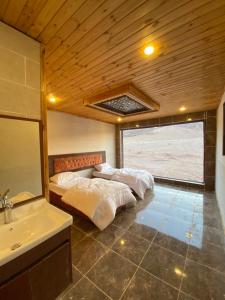 瓦迪拉姆Desert Jewel Camp的配有2张床的带水槽和镜子的客房