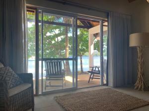 Utungake同安海滩度假村的客厅配有带椅子的滑动玻璃门