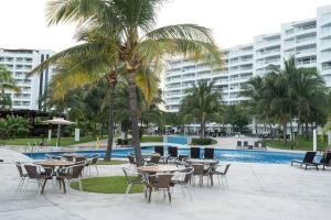 新巴利亚塔Villa Magna departamento en Nuevo Vallarta的棕榈树,游泳池旁配有桌椅