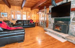 Algonquin HighlandsPine Springs Retreat with Hot Tub Steam Room Lake Kushog的客厅配有皮革家具和壁炉