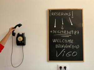 庞特维德拉Casa nueva en Vigo con Jacuzzi y chimenea的一个人在墙上拿着电话和标志