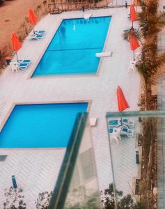 塞得港Porto Said شاليه ملكى صف اول بحر بورتو سعيد的享有2个带遮阳伞和椅子的游泳池的上方景色