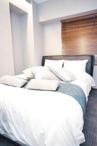 东京Hotel Plaisir Akihabara的一间卧室配有带白色床单和枕头的床。