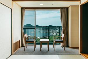 HikariKAMENOI HOTEL Setouchi Hikari的客房设有带桌椅的阳台。