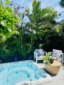 悉尼Bondi Boho House Jacuzzi PoolSpa HolidayRento的天井上的热水浴池,配有两把椅子和树木