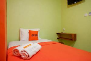 梭罗KoolKost @ Inep Kayu Jebres的床上有橙色和白色的毛巾