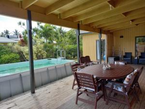 拉罗汤加Eve and Sandys Holiday Home的木甲板,配有桌子和游泳池