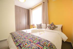 内罗毕Lantern Serviced Apartments的一间卧室配有一张带彩色毯子的床
