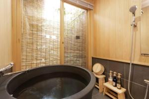 京都ゲストハウス至の宿 Shibainu-Themed Guesthouse的带窗户的浴室内的黑色大浴缸