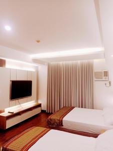 达沃市Cozy Suite Studio type condo in Matina Enclaves的酒店客房设有两张床和一台平面电视。