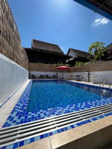 琅勃拉邦Little Friendly Guest House and Swimming Pool的一座建筑物边的蓝色瓷砖游泳池