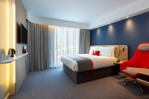 布里奇沃特Holiday Inn Express Bridgwater M5, Jct24, an IHG Hotel的酒店客房,配有一张床和一张红色椅子