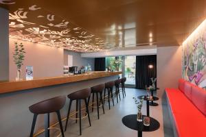 巴塞尔VISIONAPARTMENTS Basel Nauenstrasse - contactless check-in的餐厅内的酒吧,配有红色的沙发和凳子