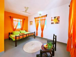 南威Frangipani House Nungwi Zanzibar的一间卧室拥有橙色和白色的墙壁,配有一张床和一张桌子