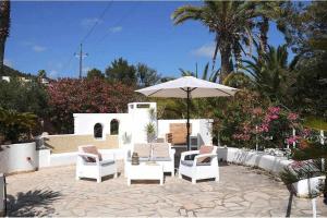 圣埃乌拉利亚Gorgeous Villa near Ibiza centre的庭院配有白色的椅子和遮阳伞。