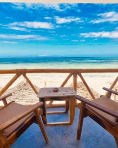 布韦朱Helwas Zanzibar Beach Hotel的海滩上的野餐桌和两把椅子