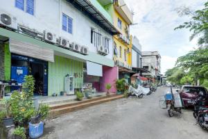 名古屋SPOT ON 91879 Emes Jaya Homestay的街道上有许多色彩缤纷的建筑和摩托车