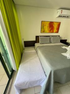 嘎林海斯港Suíte na beira-mar do Resort Marulhos Muro Alto Porto Galinhas的绿窗帘间内的两张床