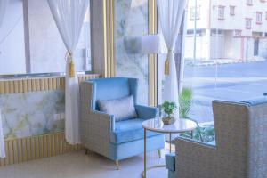 艾卜哈فندق واي هوتل的窗户客房内的蓝色椅子和桌子