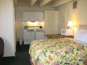 弗吉尼亚海滩Cutty Sark Efficiencies and Historic Cottage's的一间卧室配有一张床铺和一张桌子,还设有一间厨房