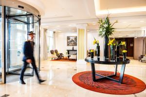 谢西雷拉斯Spa谢尔西瓦尔多欧洲酒店的一个人在大堂里散步,一边拿着鲜花桌子