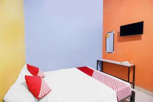 名古屋SPOT ON 91887 Penginapan Rindu的一间卧室配有一张带红色枕头的床