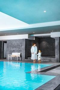 谢西雷拉斯Spa谢尔西瓦尔多欧洲酒店的站在游泳池旁的女人和孩子