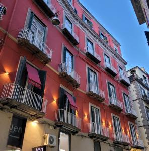 那不勒斯齐亚贾魅力酒店的一座红色的建筑,旁边设有阳台