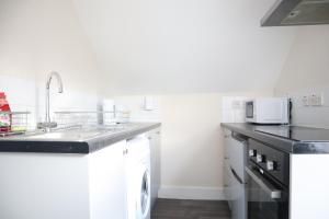South NorwoodTwelve Thirty Serviced Apartments - 1 Croydon的白色的厨房配有水槽和洗碗机