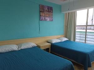 伊拉普阿托Hotel Viena的配有两张床铺的蓝色墙壁和窗户