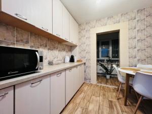 苏恰瓦Altheda Living Tineretului E8的厨房配有白色橱柜和桌椅
