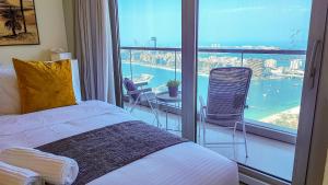 迪拜Exquisite, luxe 1BD Apartment, Unparalleled Sea Views, Prime Dubai Marina Location & Full Kitchen by "La Buena Vida Holiday Homes的一间卧室设有一张床和一个美景阳台