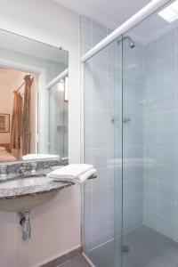 圣保罗罗哈斯全套房酒店的一间带玻璃淋浴和水槽的浴室