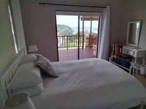 Glen Eden2 Bedroom Guest Suite at A-frame Glengariff Beach的一间带白色床的卧室和一个阳台