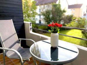 罗伊特林根Top-Apartment mit Parkplatz und Balkon的阳台上的桌子上装有红色花卉的花瓶