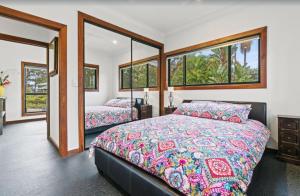 NeranwoodGold Coast Tree Houses的一间卧室设有两张床和两个窗户。