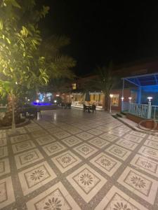 Dawmat al Jandalفندق ادوماتو ADOMATo HOTEl的夜间铺着瓷砖的庭院,配有桌子和树木