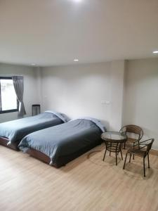 宋卡IHome Hostel Hatyai的一间卧室配有两张床和一张桌子及椅子